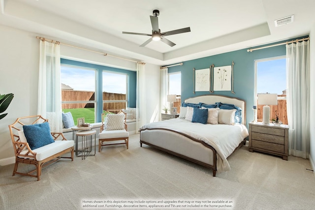 bedroom featuring light carpet, ceiling fan, and a raised ceiling