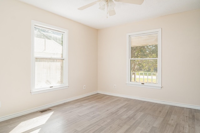 empty room featuring plenty of natural light, ceiling fan, and light wood-type flooring