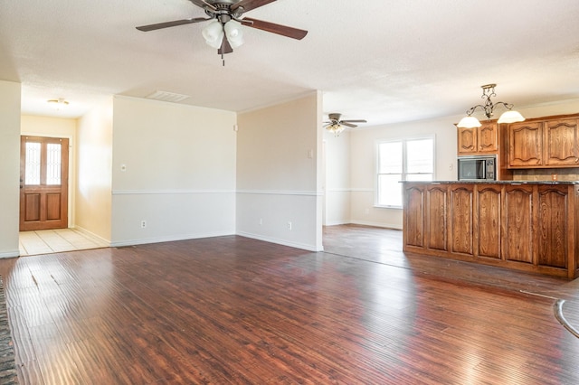 unfurnished living room with ceiling fan with notable chandelier, wood-type flooring, and a textured ceiling