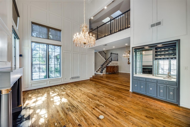 unfurnished living room with wood-type flooring, a towering ceiling, and a chandelier