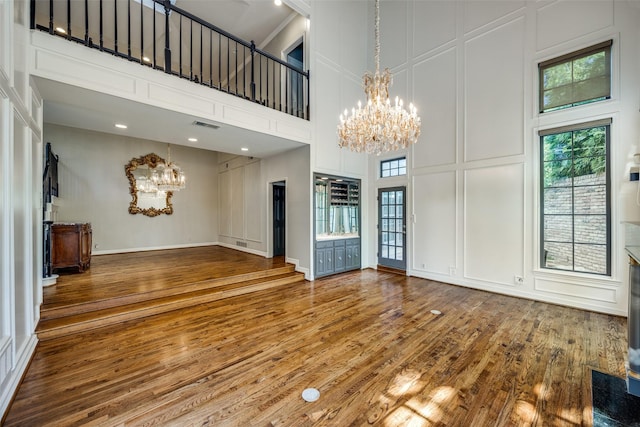 unfurnished living room featuring hardwood / wood-style floors, a high ceiling, and a notable chandelier