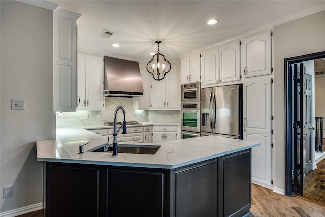 kitchen featuring white cabinetry, wall chimney range hood, kitchen peninsula, decorative light fixtures, and appliances with stainless steel finishes