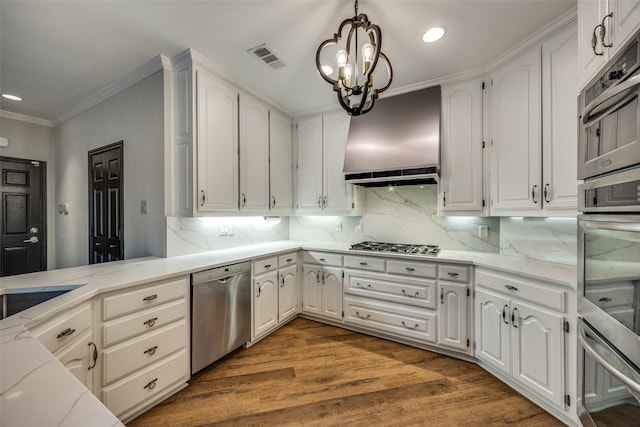 kitchen featuring hardwood / wood-style floors, hanging light fixtures, appliances with stainless steel finishes, tasteful backsplash, and white cabinetry