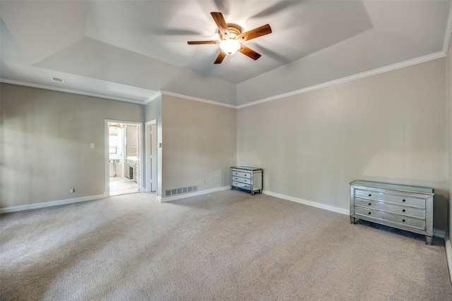 empty room with carpet, ceiling fan, ornamental molding, and a tray ceiling