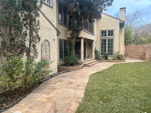 rear view of property with a yard and a balcony