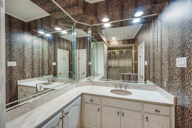 bathroom with vanity, a shower with door, and crown molding