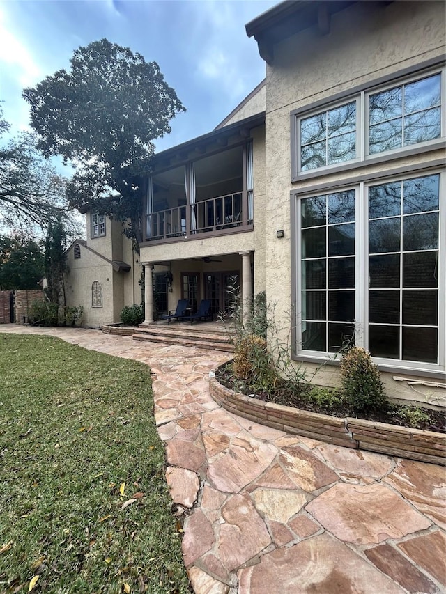 back of house featuring a balcony and a yard