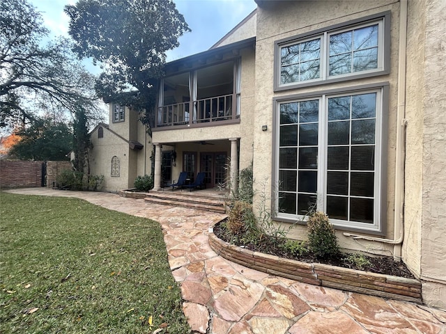 back of property featuring a lawn and a balcony