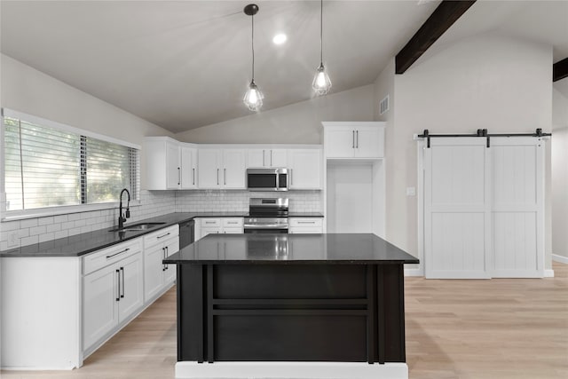 kitchen featuring white cabinets, a barn door, sink, and stainless steel appliances