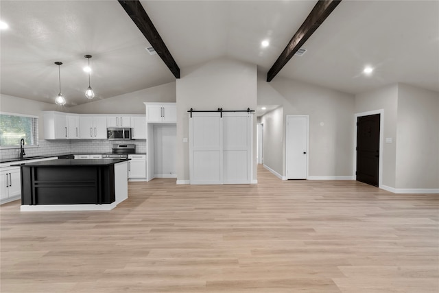 kitchen featuring a barn door, light hardwood / wood-style flooring, beamed ceiling, and stainless steel appliances