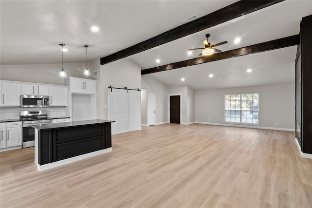 kitchen featuring stainless steel appliances, lofted ceiling with beams, a barn door, white cabinets, and light hardwood / wood-style floors