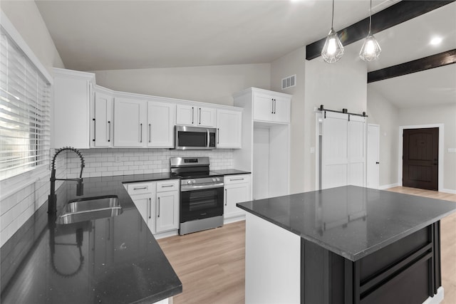 kitchen featuring a barn door, sink, a center island, and appliances with stainless steel finishes