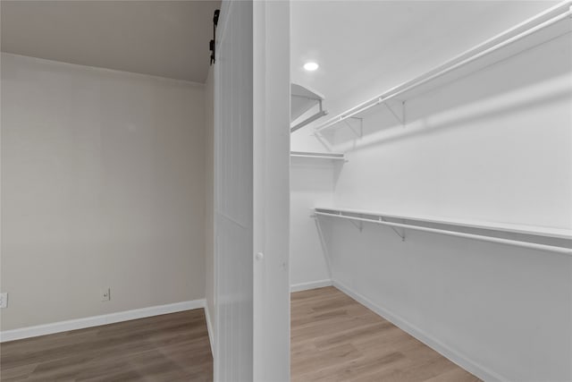 walk in closet featuring a barn door and hardwood / wood-style floors