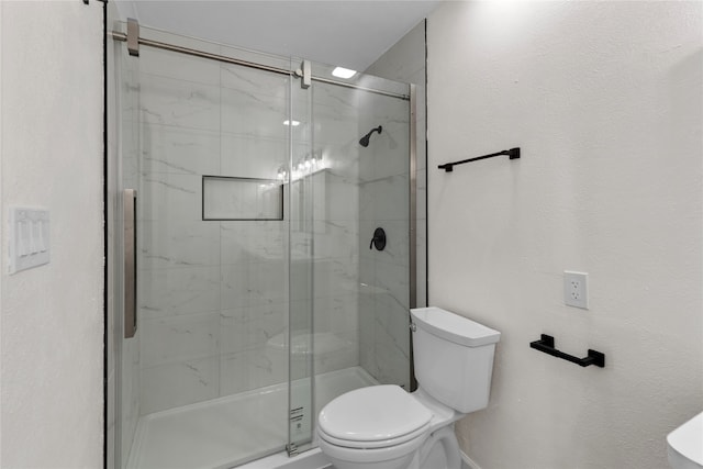 bathroom featuring a shower with door and toilet