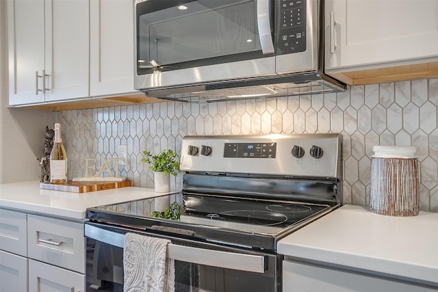 kitchen with appliances with stainless steel finishes, backsplash, and white cabinets