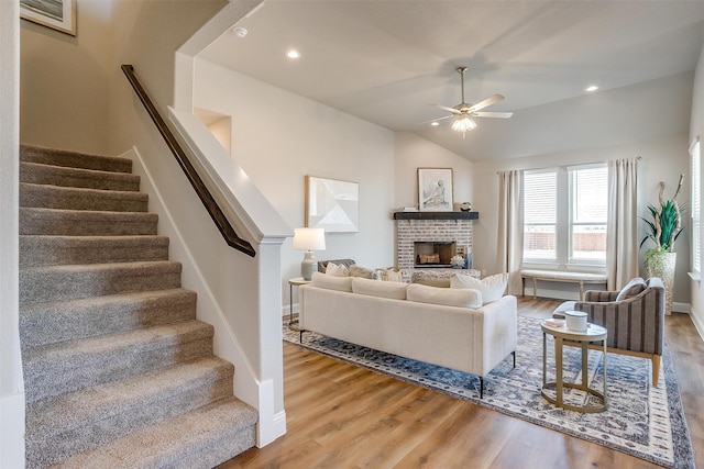 living room featuring a brick fireplace, hardwood / wood-style flooring, lofted ceiling, and ceiling fan