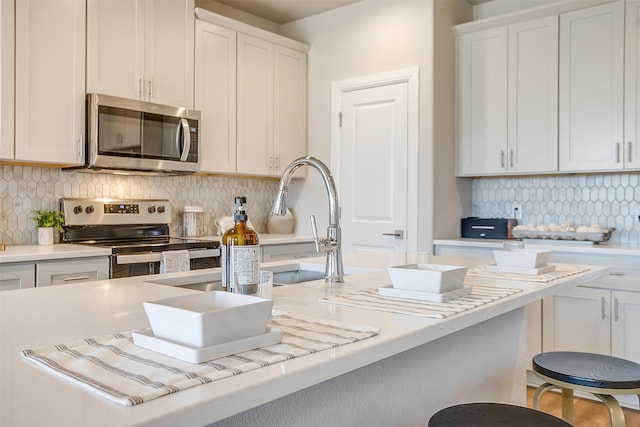 kitchen with appliances with stainless steel finishes, decorative backsplash, and white cabinetry