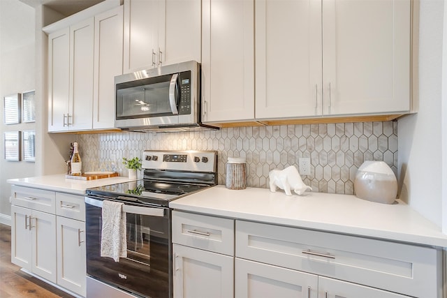 kitchen featuring stainless steel appliances, white cabinets, light wood-type flooring, and backsplash