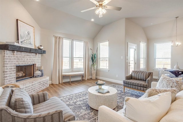 living room featuring hardwood / wood-style flooring, vaulted ceiling, a brick fireplace, and a wealth of natural light