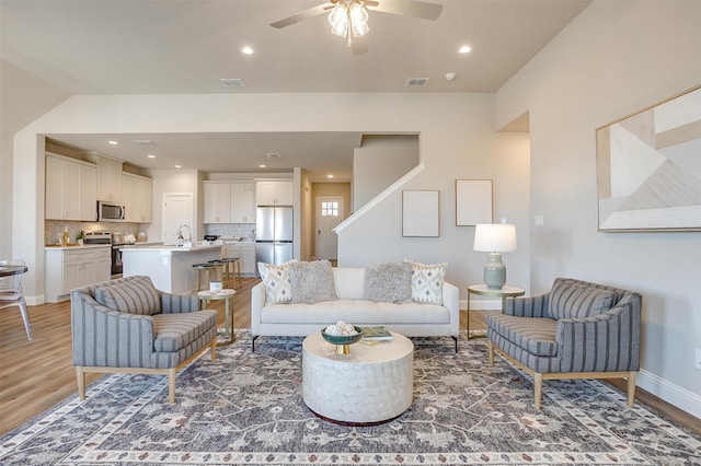 living room featuring wood-type flooring, sink, and ceiling fan