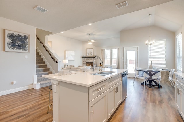 kitchen with hanging light fixtures, an island with sink, lofted ceiling, stainless steel dishwasher, and sink