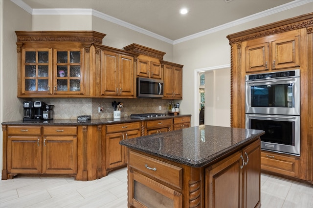 kitchen featuring stainless steel appliances, crown molding, dark stone counters, decorative backsplash, and a kitchen island