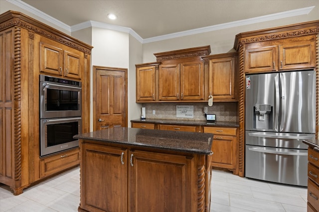 kitchen featuring appliances with stainless steel finishes, a kitchen island, dark stone counters, and crown molding