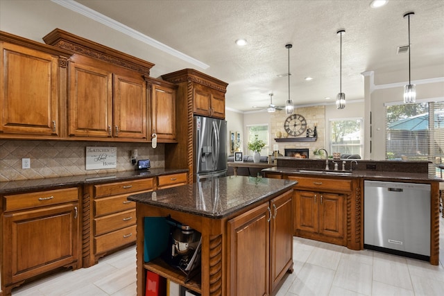 kitchen featuring a large fireplace, sink, stainless steel appliances, decorative light fixtures, and a kitchen island