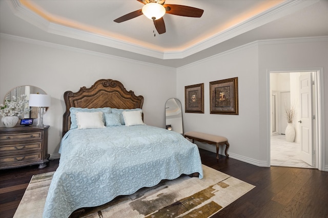 bedroom featuring connected bathroom, ceiling fan, dark hardwood / wood-style floors, crown molding, and a tray ceiling