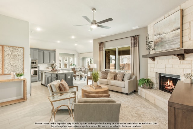 living room featuring a stone fireplace, sink, and ceiling fan