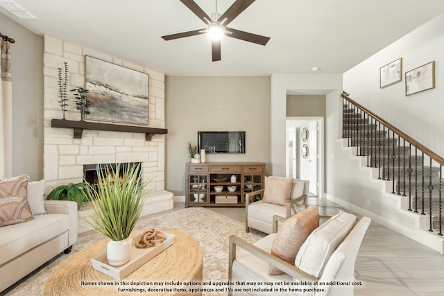 living room featuring ceiling fan and a stone fireplace