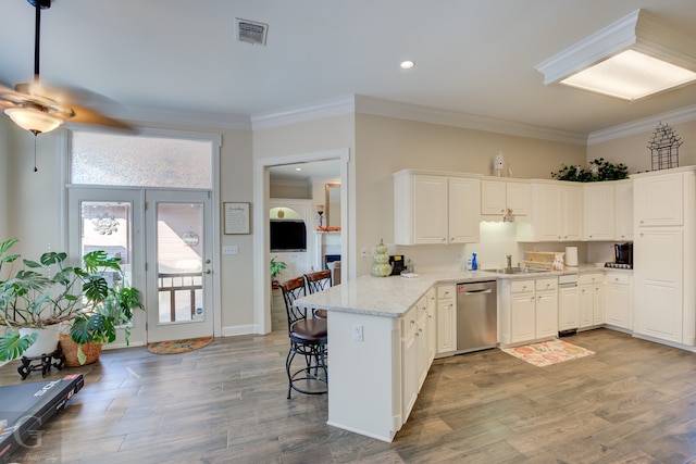 kitchen featuring a kitchen breakfast bar, white cabinets, kitchen peninsula, stainless steel dishwasher, and ornamental molding