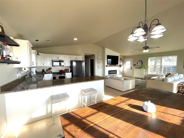 kitchen featuring white cabinets, kitchen peninsula, black appliances, lofted ceiling, and dark stone counters