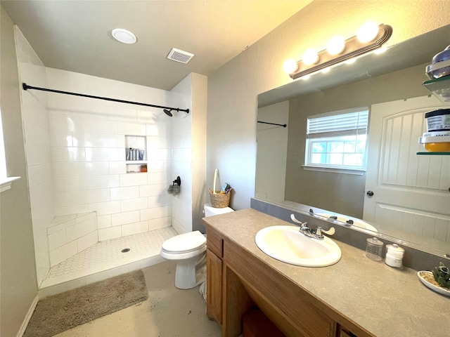 bathroom featuring tiled shower, vanity, and toilet