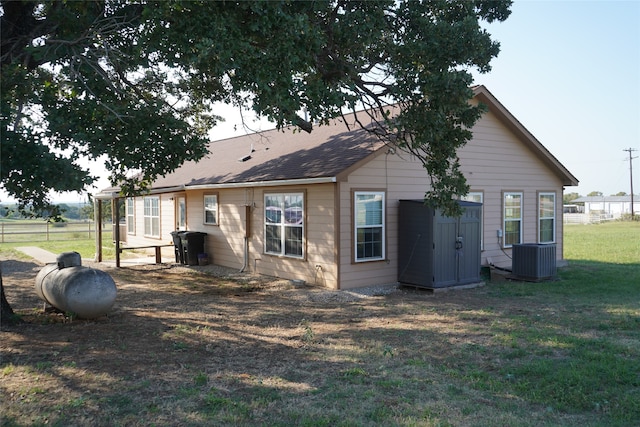 rear view of house with central AC and a yard