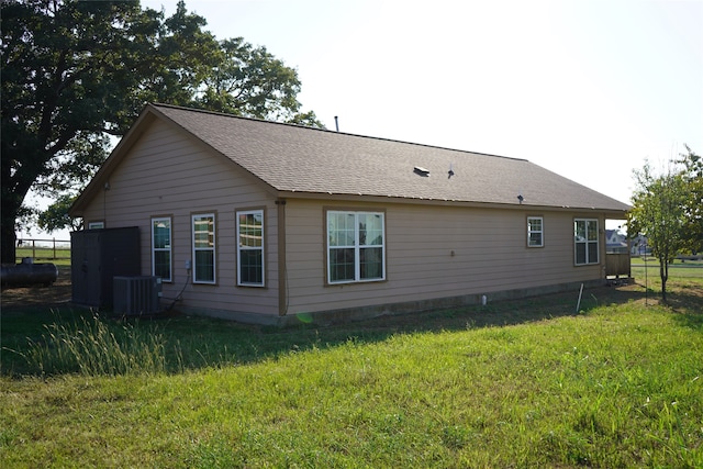 rear view of property with a lawn and central air condition unit