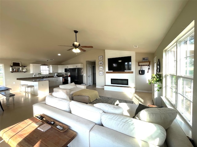 living room featuring a fireplace, vaulted ceiling, and ceiling fan