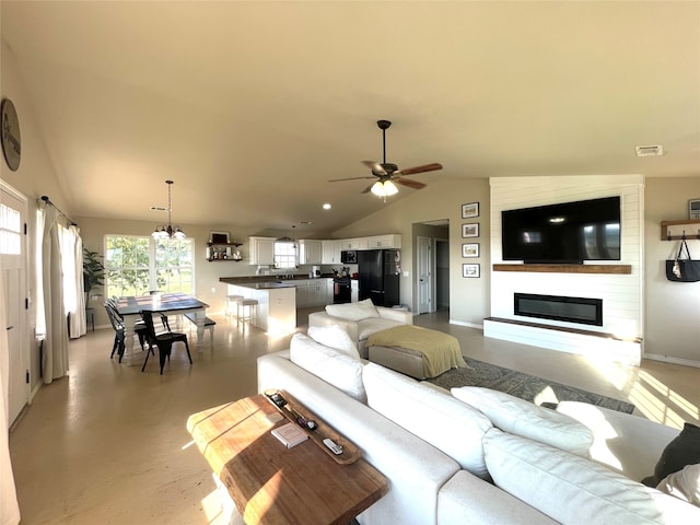 living room with ceiling fan with notable chandelier, vaulted ceiling, and a fireplace