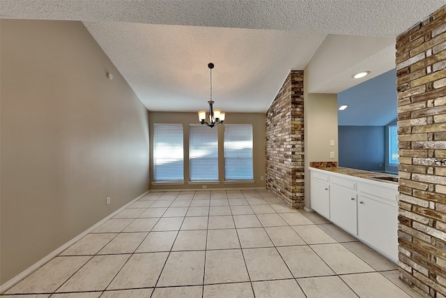 interior space featuring a textured ceiling, a notable chandelier, light tile patterned floors, and a wealth of natural light