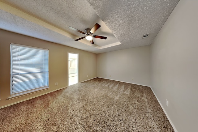 carpeted empty room with a tray ceiling, ceiling fan, and a textured ceiling