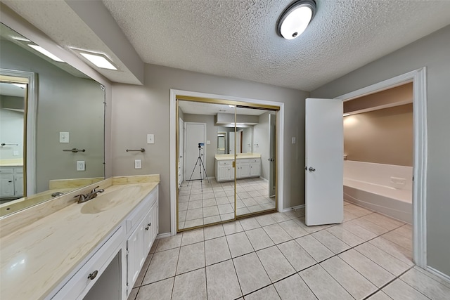 bathroom featuring a textured ceiling, vanity, a bathtub, and tile patterned floors