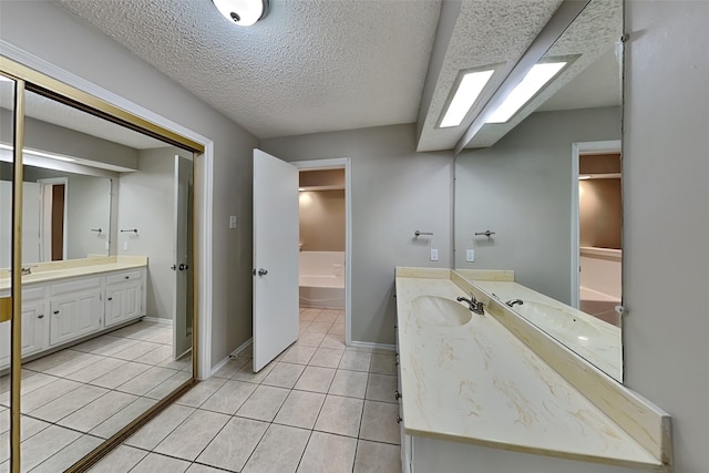 bathroom featuring tile patterned floors, a textured ceiling, vanity, and a bathtub