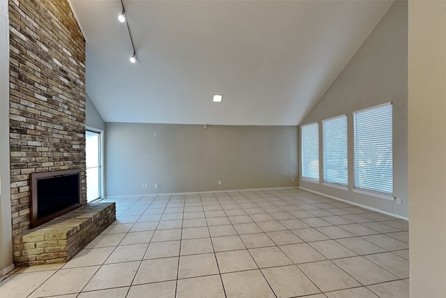 unfurnished living room with track lighting, light tile patterned flooring, high vaulted ceiling, and a healthy amount of sunlight