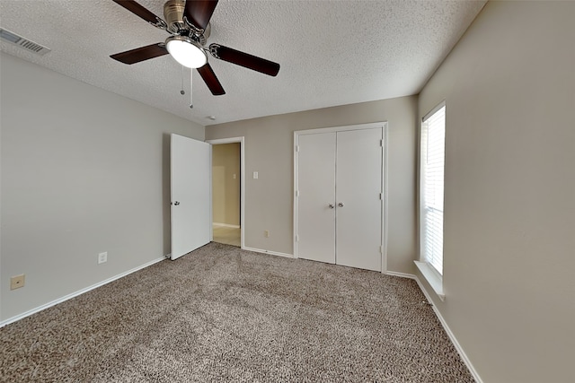 unfurnished bedroom with a textured ceiling, ceiling fan, a closet, and carpet floors