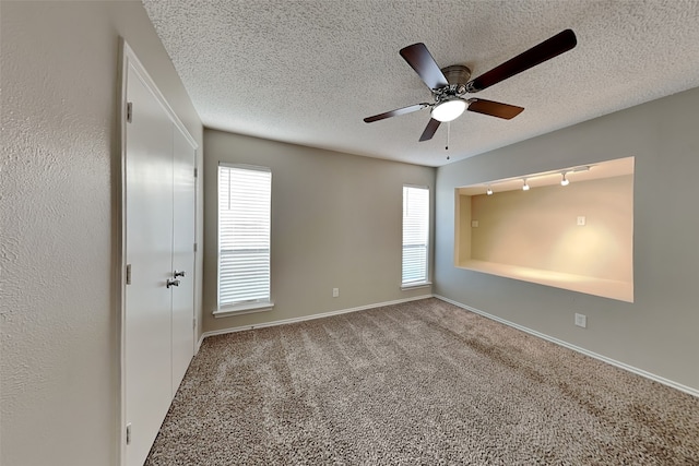 carpeted spare room with a textured ceiling and ceiling fan