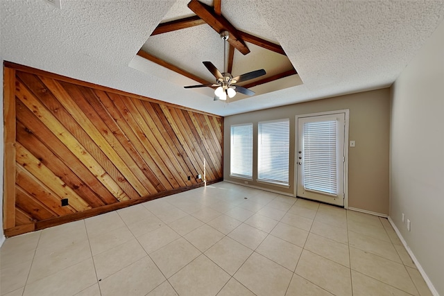 tiled empty room with ceiling fan, a textured ceiling, and wood walls