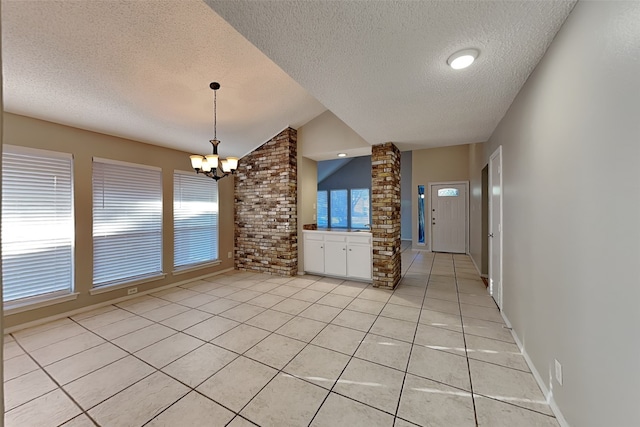 kitchen featuring light tile patterned floors, vaulted ceiling, a textured ceiling, a notable chandelier, and ornate columns