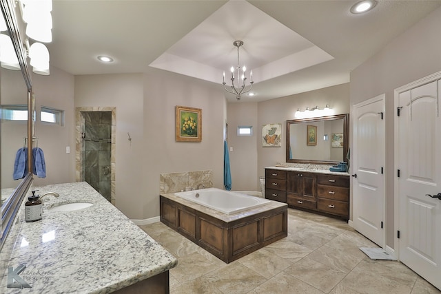 bathroom with an inviting chandelier, vanity, plus walk in shower, and a tray ceiling