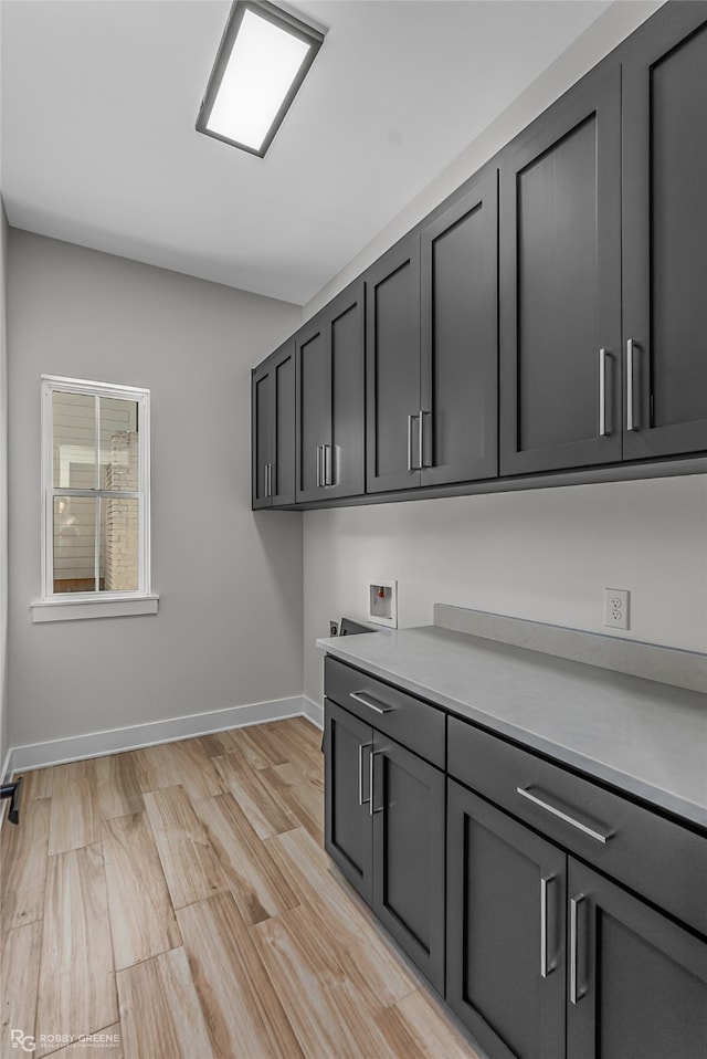 clothes washing area featuring washer hookup, cabinets, and light hardwood / wood-style floors