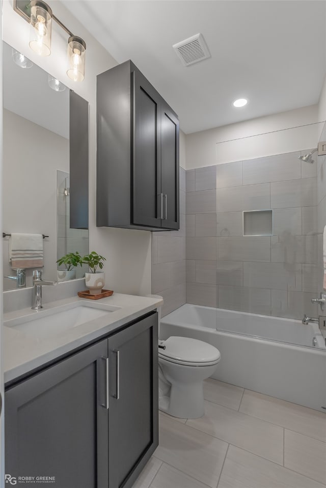 full bathroom featuring tile patterned floors, tiled shower / bath combo, vanity, and toilet